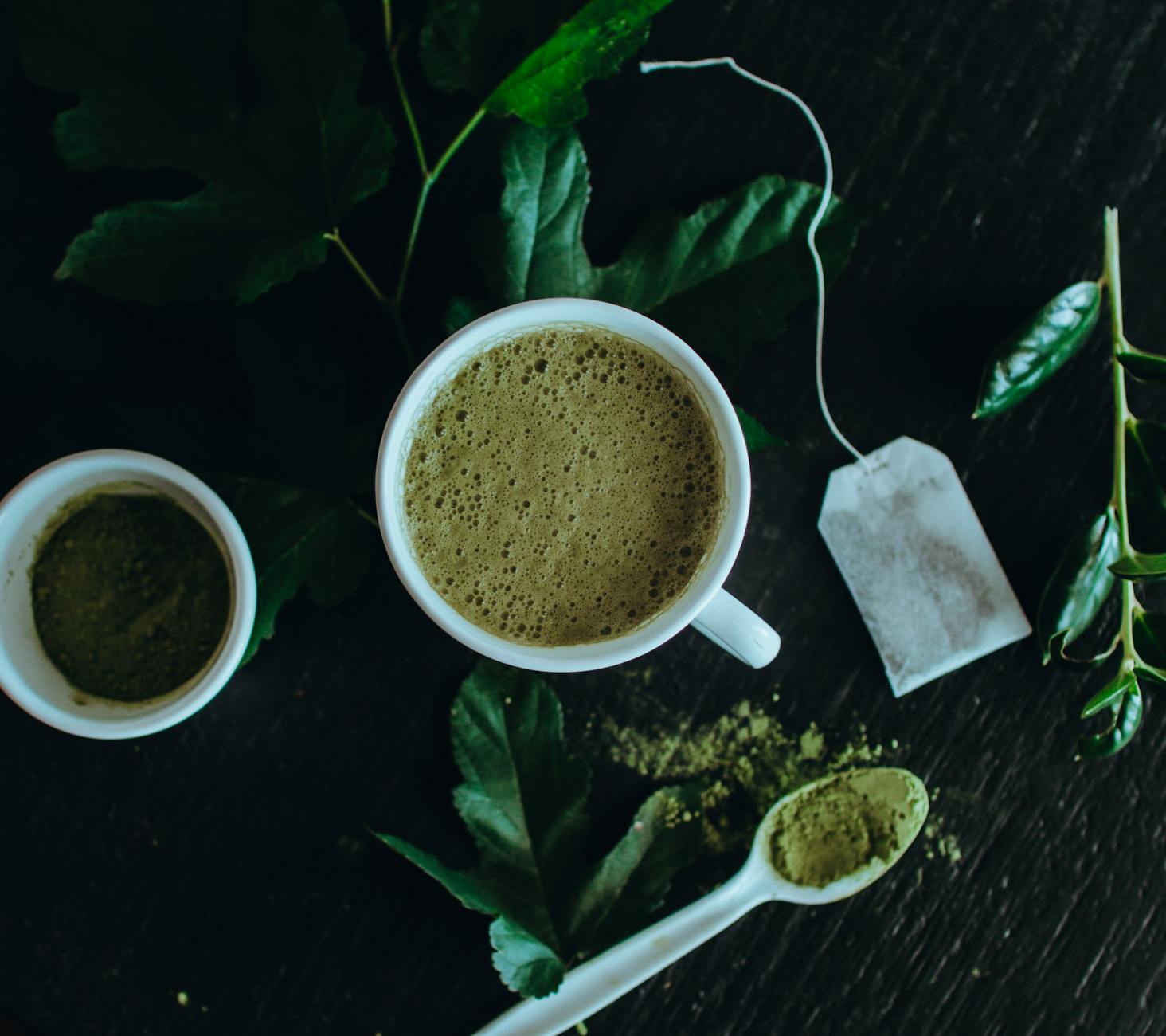 Frothy matcha latte in a ceramic cup with matcha powder