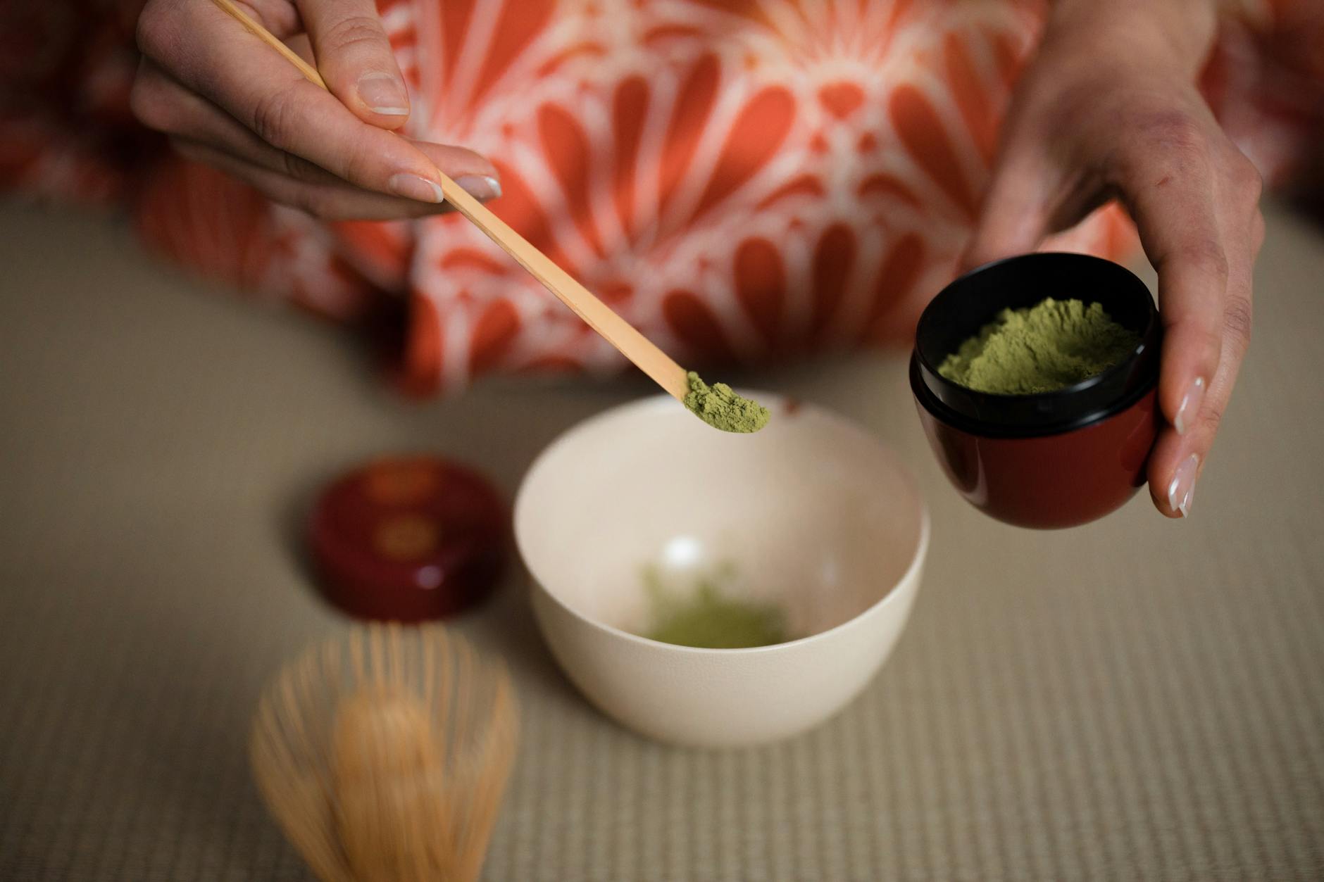 A cup of Japanese green tea with tea leaves on a wooden tray
